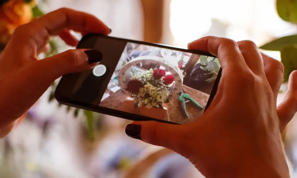 Instagram für Autoren – Smartphone fotografiert ein Blumenmotiv für Social Media