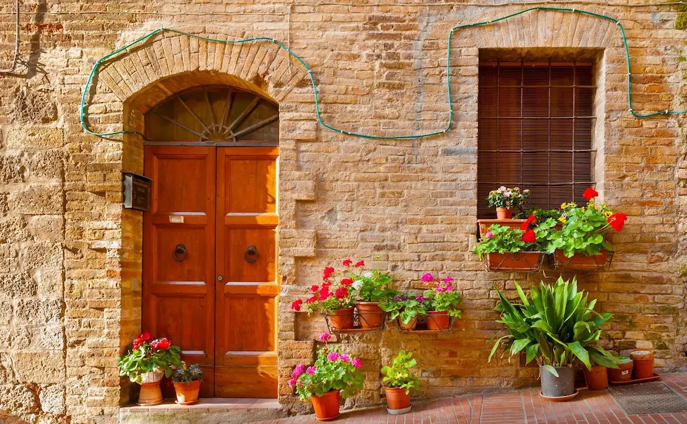 Haus kaufen in Italien – Eingang eines historischen Hauses mit Blumen in einer italienischen Altstadt