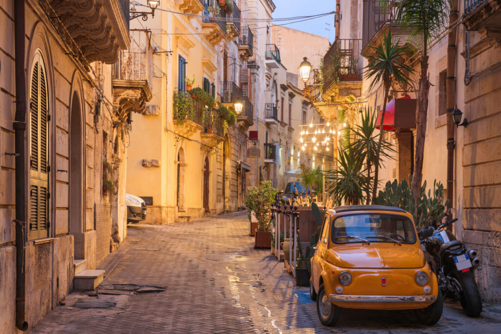 Kleine italienische Altstadtgasse mit Fiat 500 als Symbol für die Sehnsucht nach dem Leben in Italien