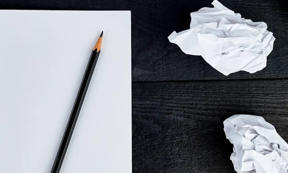 Buchprojekt pausieren – leeres Blatt mit Bleistift und zerknülltem Papier