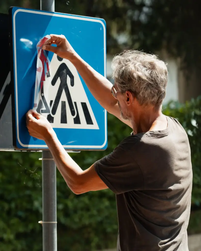 Clet Abraham bringt eine Street-Art-Folie auf ein Verkehrsschild an – Toskana Wochenschau