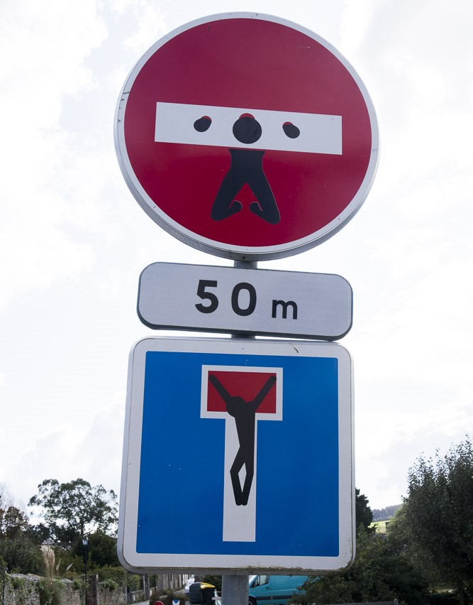 Zwei von Clet Abraham gestaltete Verkehrsschilder in Florenz zeigen eine Kreuzigung auf einem Sackgassen-Schild und eine Figur an einem Einfahrt-verboten-Schild.