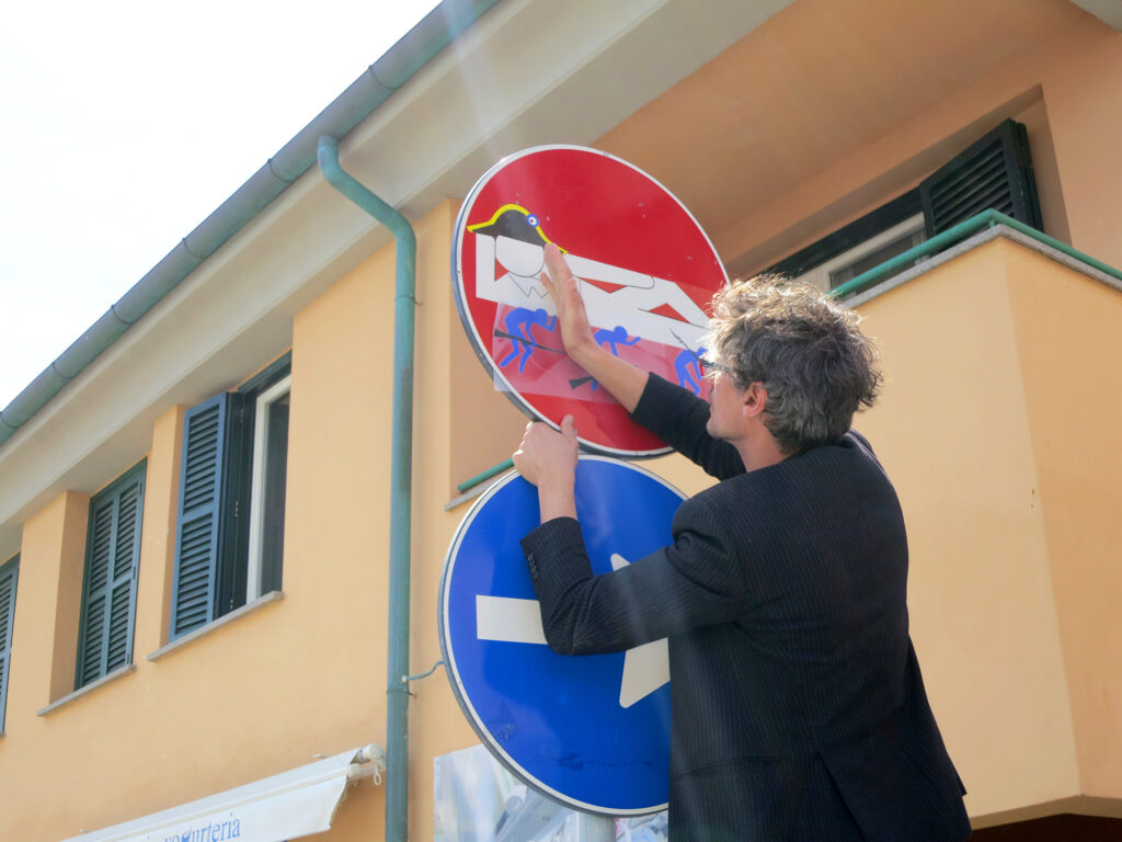 Clet Abraham bringt in der Toskana Wochenschau eine seiner Street-Art-Arbeiten auf einem Verkehrsschild in Florenz an