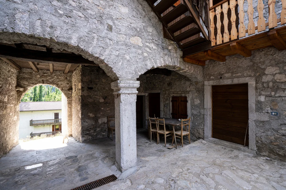 Immobilie in Italien – alter Innenhof aus Naturstein mit Holzbalkon und Rundbogen