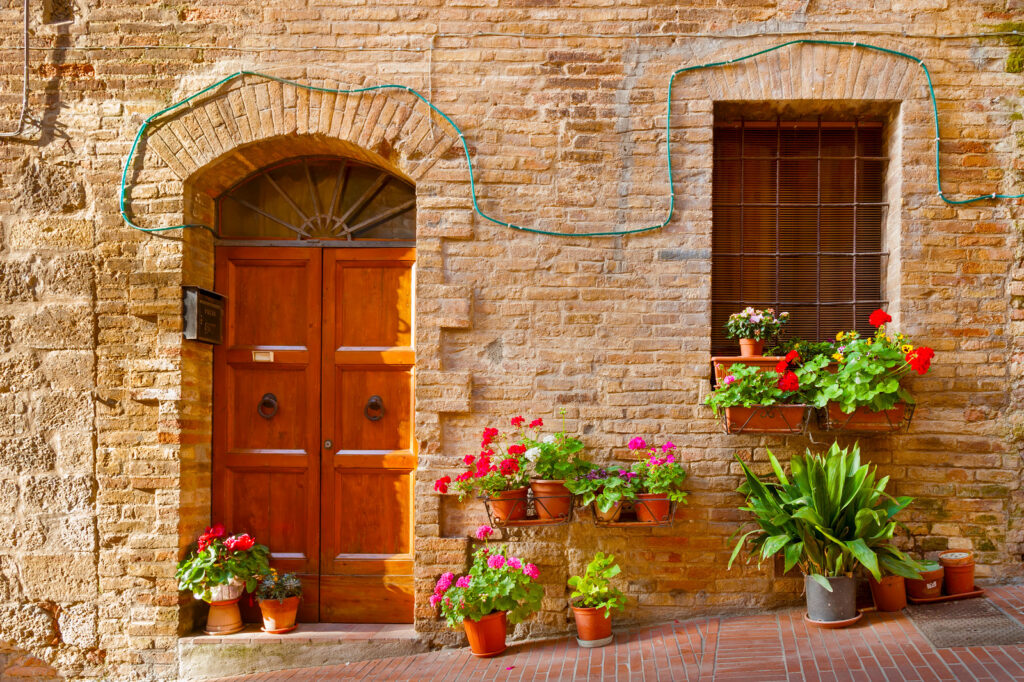 Hübsche Haustür mit Blumen an einem Natursteinhaus in Italien – Immobilie in Italien kaufen