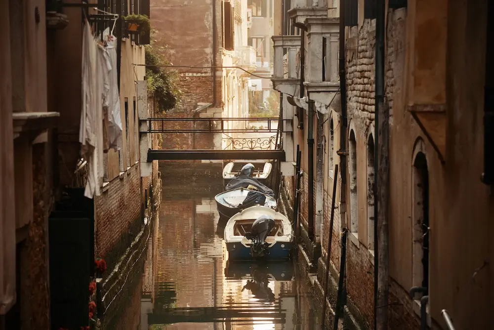 Wenn die Gondeln Trauer tragen – dunkler Kanal mit Booten in Venedig