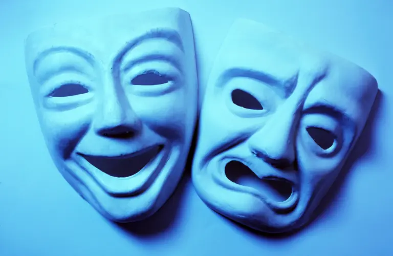 Schöne Worte sind nicht immer wahr – lachende und traurige Theatermaske als Symbol für Schein und Wahrheit