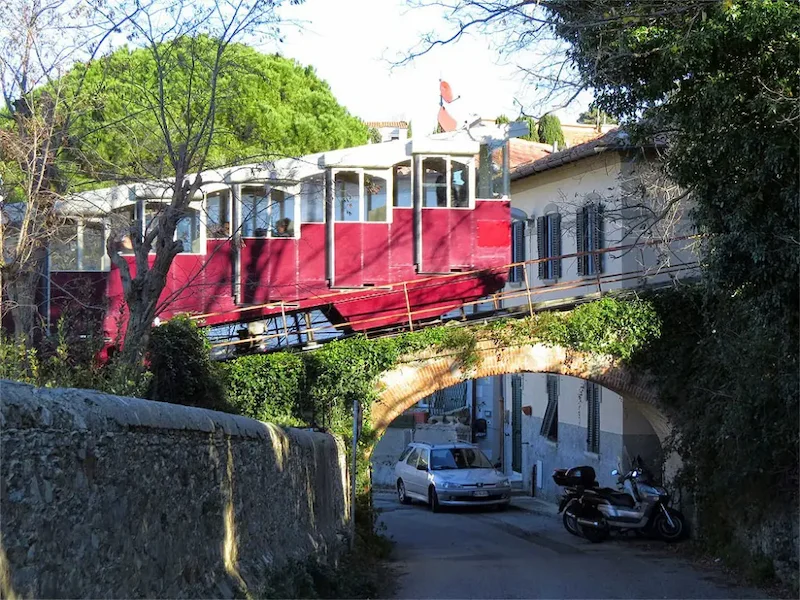 Toskana Wochenschau: Roter Wagen der Funicolare di Montenero auf einer Brücke über einer Wohnstraße