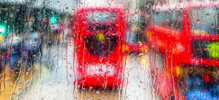 Warum ich schreibe – roter Bus hinter einer regennassen Scheibe als Bild für einen monotonen Arbeitsalltag