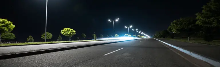 Gedankenstrich vs Bindestrich – nächtliche Straße mit langen Lichtspuren und unterbrochenen Fahrbahnmarkierungen