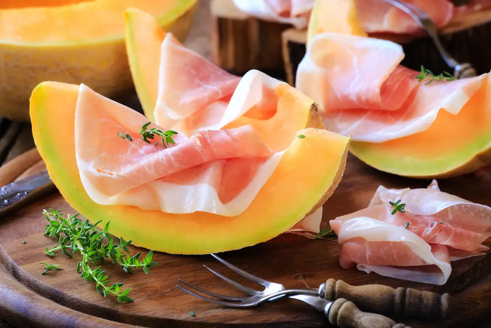 Mediterrane Küche – Melonenspalten mit Prosciutto und frischen Kräutern