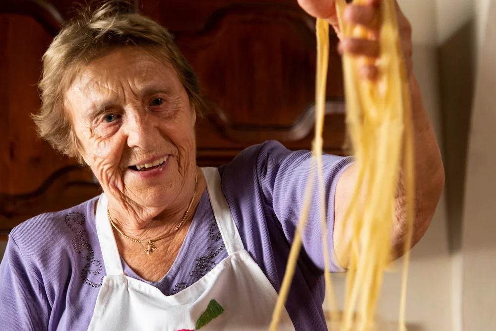 Typisch italienisch – ältere Italienerin mit frischer Pasta als Symbol für Tradition und Küchenregeln